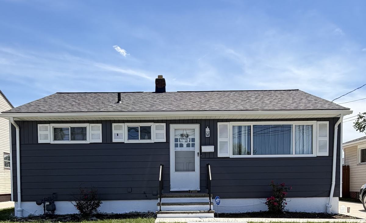 The same ranch house repainted in deep slate, with the white shutters, trim and door still bright.