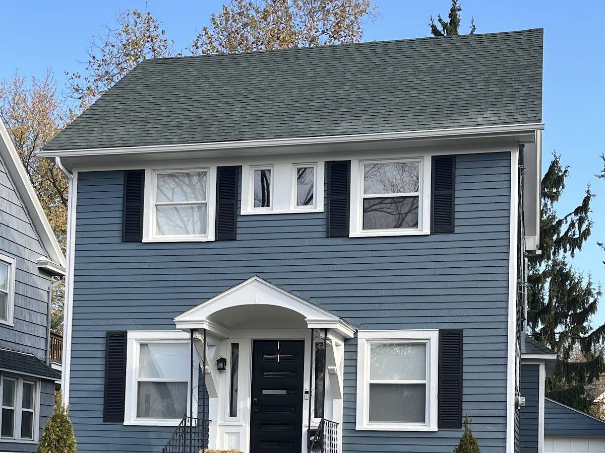 A two-story house with slate-blue siding, black shutters, white trim and a black front door under a white portico.